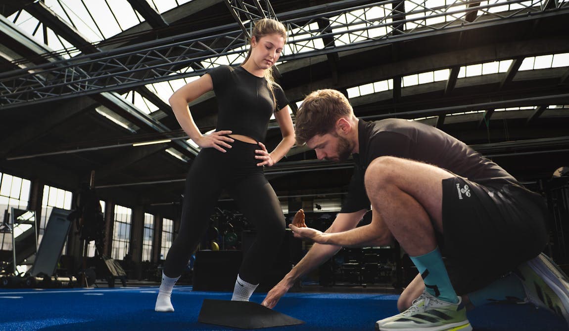 Trainer mit Frau bei Erläuterung der richtigen Fußstellung bei PhysioSport Köln.