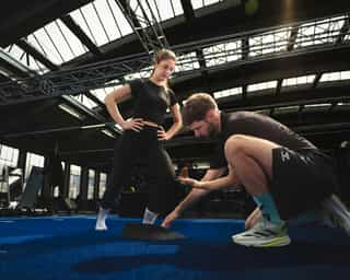 Trainer von PhysioSport Köln mit Frau bei Erläuterung der richtigen Fußstellung.