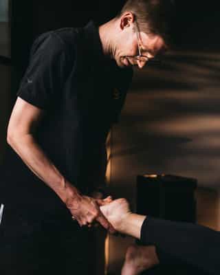 Mitarbeiter mobilisiert die Füße einer Patientin.