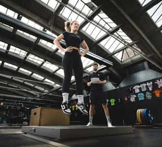 Trainer von PhysioSport Köln mit Sportlerin bei Sprunganalyse auf einer Matte.