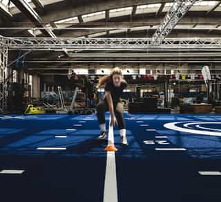 Sportlerin beim Sprint- und Koordinationstraining mit Hütchen in der Trainingshalle von Physiosport Köln.