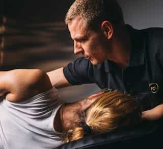 Trainer mobilisiert Rumpfmuskulatur einer Patientin in der osteopathischen Therapie bei Physiosport Köln.