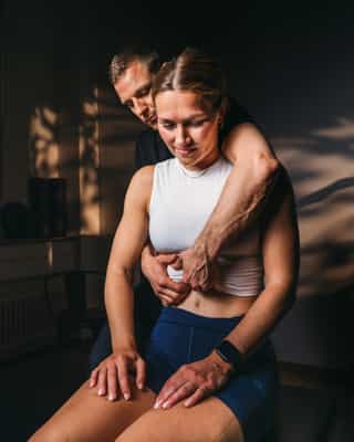 Trainer mobilisiert die Wirbelsäule einer Patientin.