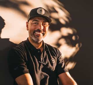 Das Bild zeigt einen Mitarbeiter von PhysioSport Kölan, der lächelnd auf einem Fahrrad sitzt.