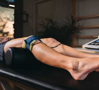 Physikalische Therapie bei PhysioSport: Patientin mit Elektroden am Knie auf Liege, Elektrotherapiegerät daneben.