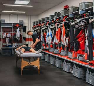 Zu sehen ist ein Einblick in die Mannschaftskabine der Kölner Haie, den Partnern von Physiosport Köln. In der Mitte steht eine Liege mit einem daraufliegendem Spieler, der behandelt wird.