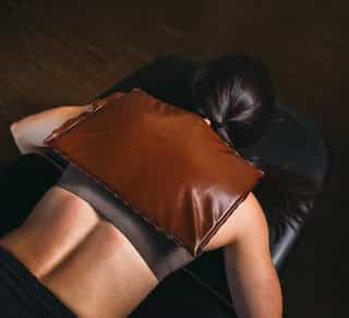 Wärmetherapie bei PhysioSport zur Muskelentspannung mittels Fangokissen. Patientin liegt und Fangokissen befindet sich auf dem Rücken.