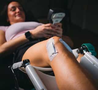 Patientin liegt auf einer Behandlungsliege von PhysioSport Köln. Es ist zu sehen, wie das Knie bei Arthrose behandelt werden kann..