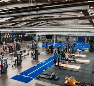 Zu sehen ist eine große Trainingsanlage von Physiosport Köln mit Matten, Geräten und Menschen, die daran trainieren.