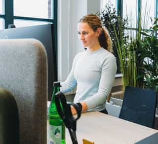 Zu sehen ist der Einblick in einen offenen Arbeitsplatz bei Physiosport Köln. Dort sitzt eine Mitarbeiterin konzentriert und aufmerksam am Computer.