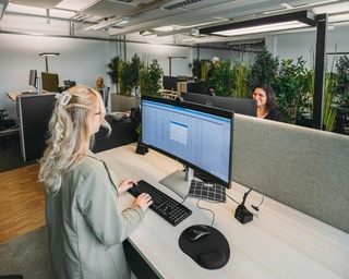 Zu sehen ist der Einblick in einen offenen Arbeitsplatz bei PhysioSport Köln. Dort sitzt eine Mitarbeiterin am Computer und im Hintergrund andere Arbeitsplätze.