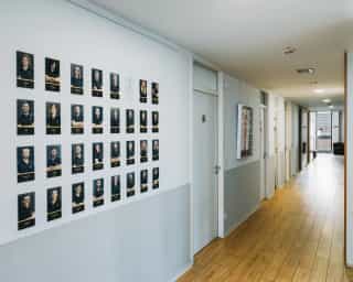 Einblick in einen den Flur bei PhysioSport Köln. Zu sehen ist eine Bildergalerie der Mitarbeiter an der Wand.
