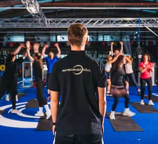 Zu sehen ist ein Trainer von PhysioSport Köln, der gerade mit einer Gruppe von Patienten ein Gruppentraining durchführt.