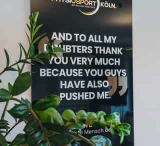 Zu sehen ist eine Tafel an der Wand von Physiosport Köln mit der Arbeitsphilosophie des Team.