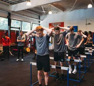 Zu sehen ist eine Gruppe von Sportlern beim Indoor-Sprungtraining. Das Training wird angeleitet durch einen Physiotherapeuten von PhysioSport Köln.