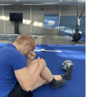 Zu sehen ist ein Sportler schräg von hinten gesehen bei PhysioSport Köln, der sich vor Schmerzen an sein Knie fasst.