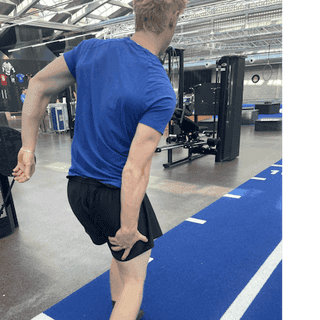 Man sieht einen Sportler bei PhysioSport Köln, der sich nach einer Muskelverletzung an sein Bein greift.