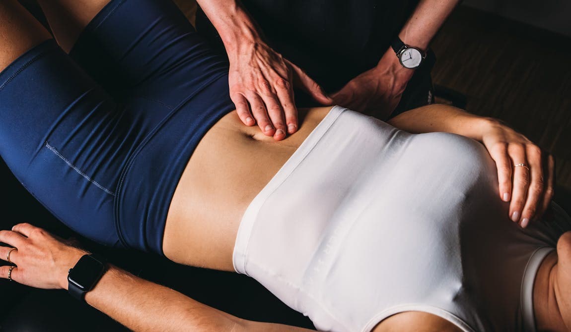Physiotherapeut von PhysioSport Köln behandelt eine Sportlerin mit manueller Lymphdrainage im Rumpfbereich.