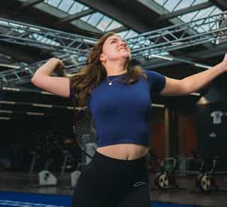 Sportlerin während Tennisübungen bei PhysioSport Köln nach Schulterbeschwerden.