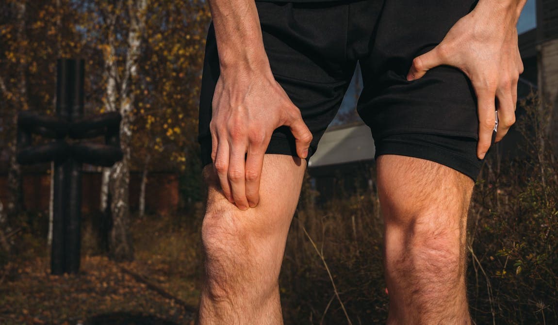 Sportler fasst sich ans Knie aufgrund von Knieschmerzen.