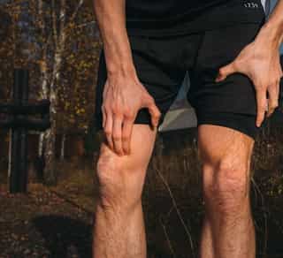 Sportler fasst sich ans Knie aufgrund von Knieschmerzen.