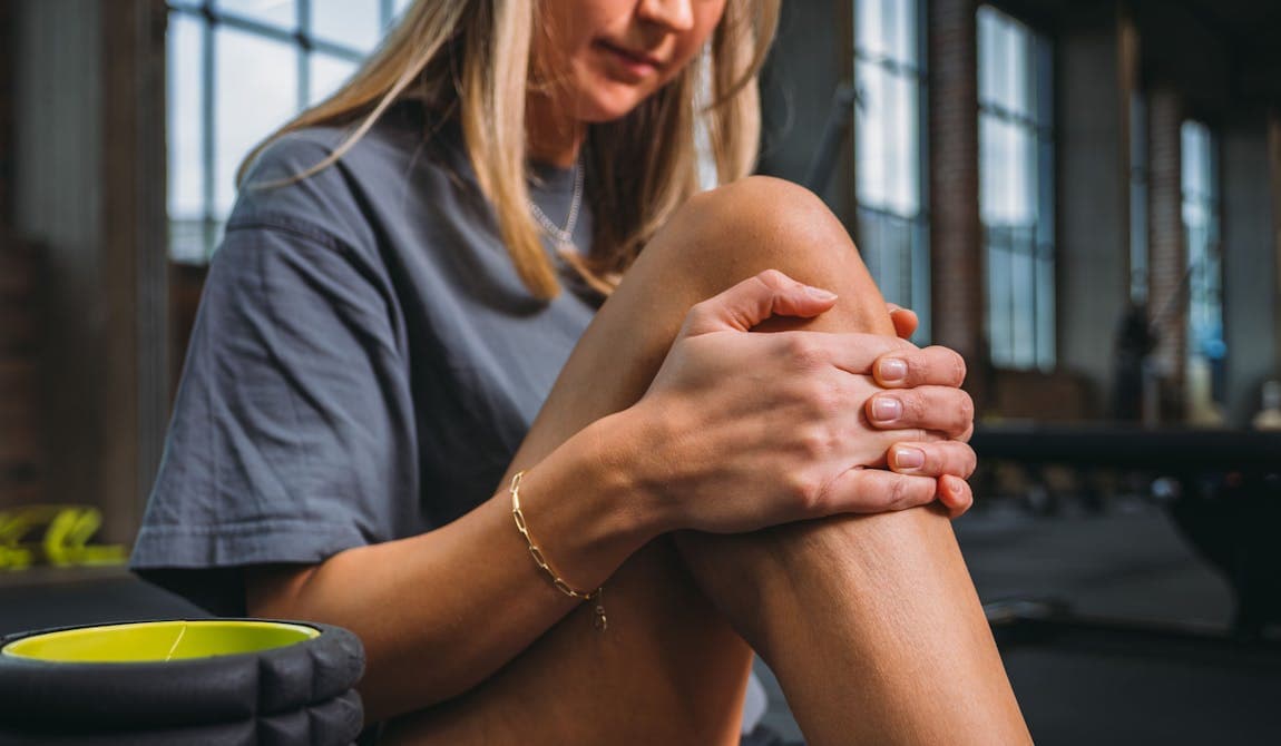 Sportlerin fasst sich ihr rechtes Knie aufgrund von Knieschmerzen.